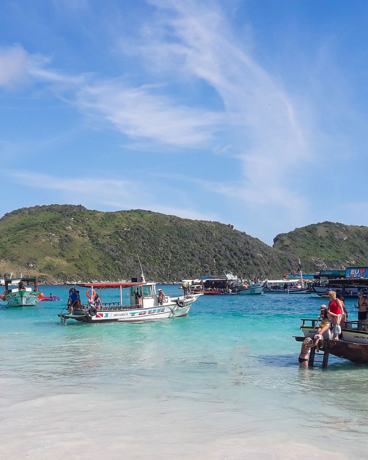 Praia do Farol, one of the best beaches in Arraial do Cabo, on a sunny day, featuring blue, crystal-clear waters and many anchored boats.