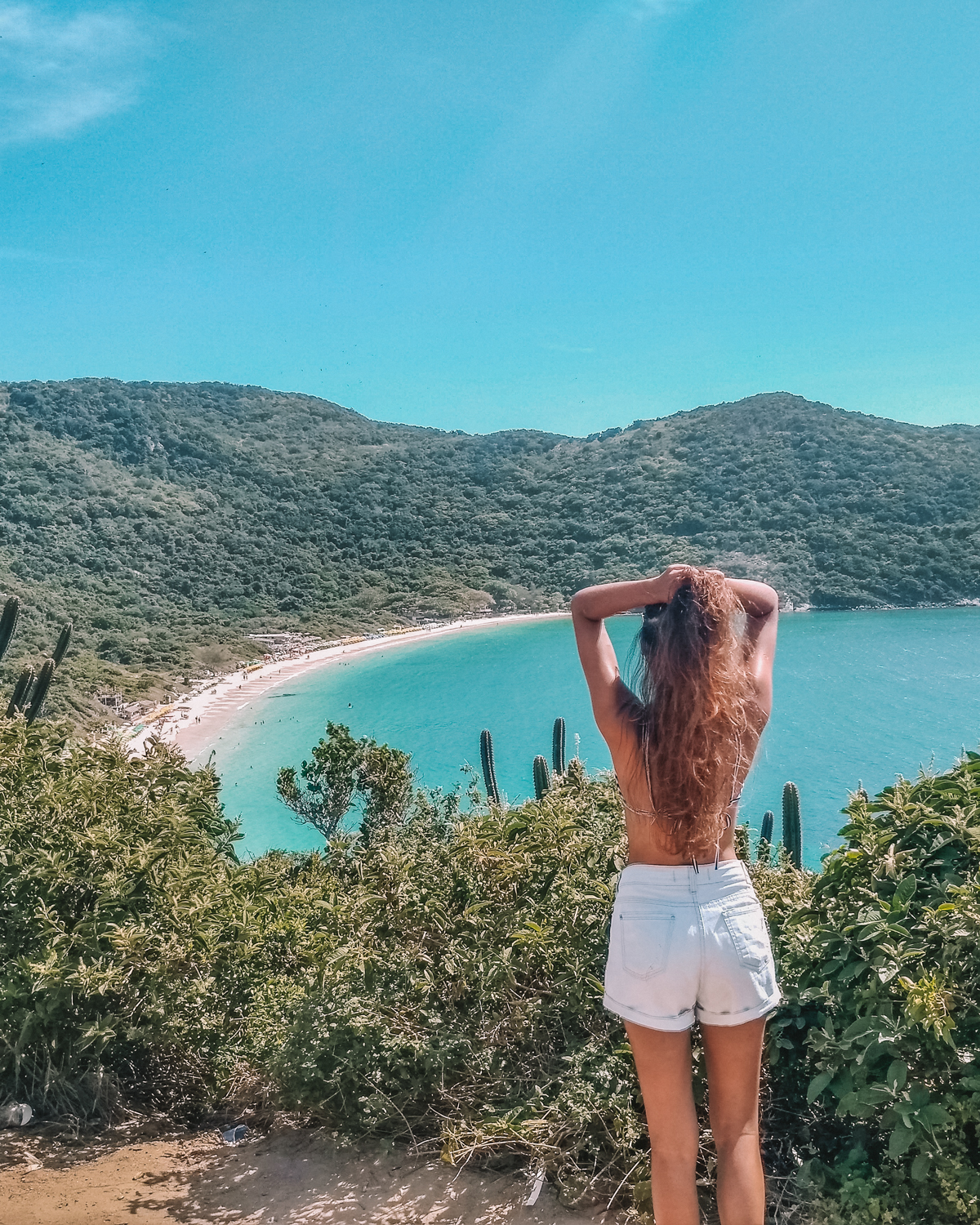 A woman admiring the view of Praia do Forno in Arraial do Cabo from a natural viewpoint, perfect for nature lovers and photographers.