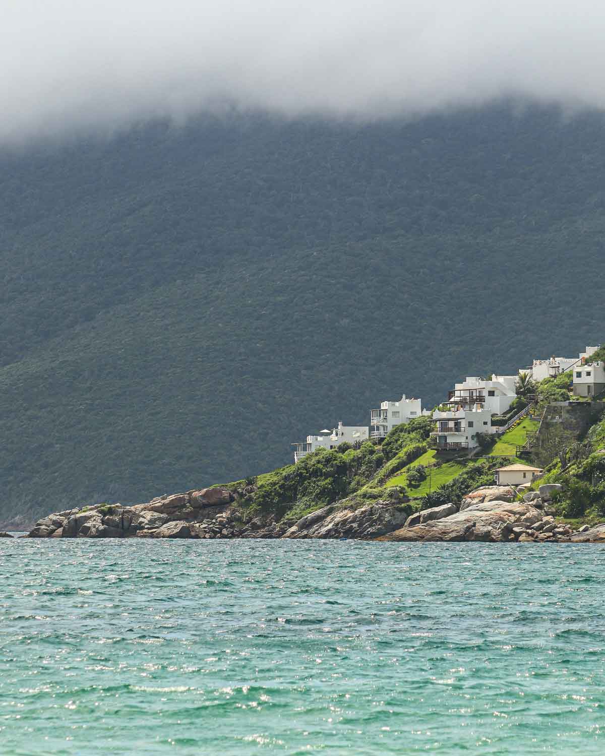 A cluster of modern white buildings overlooking the blue waters, located in the best region for renting vacation homes in Arraial do Cabo, Pontal do Atalaia.