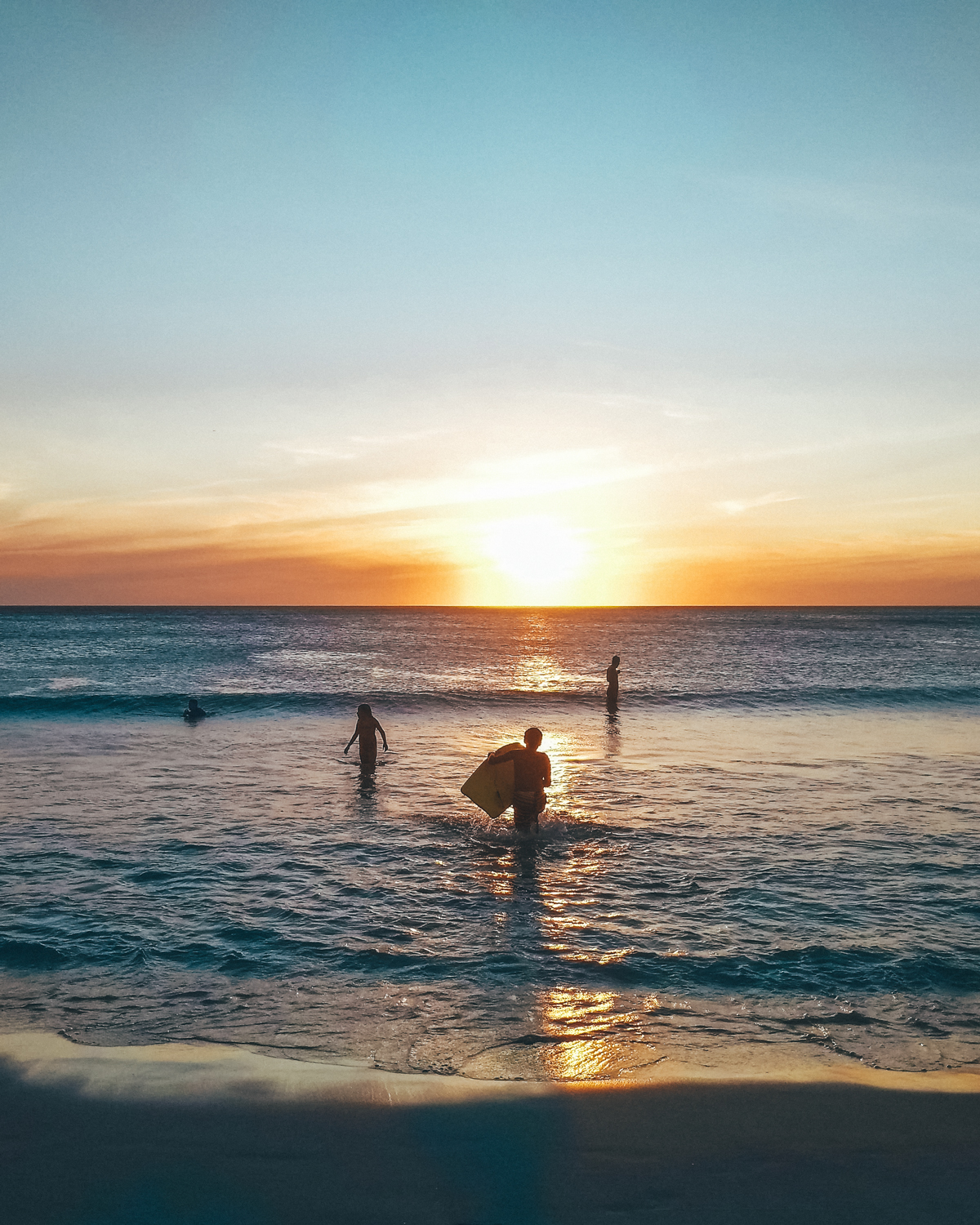 A magical sunset at Praia Grande in Arraial do Cabo with people enjoying the water, capturing the beauty and tranquility of the place, perfect for winding down after a day of exploration.